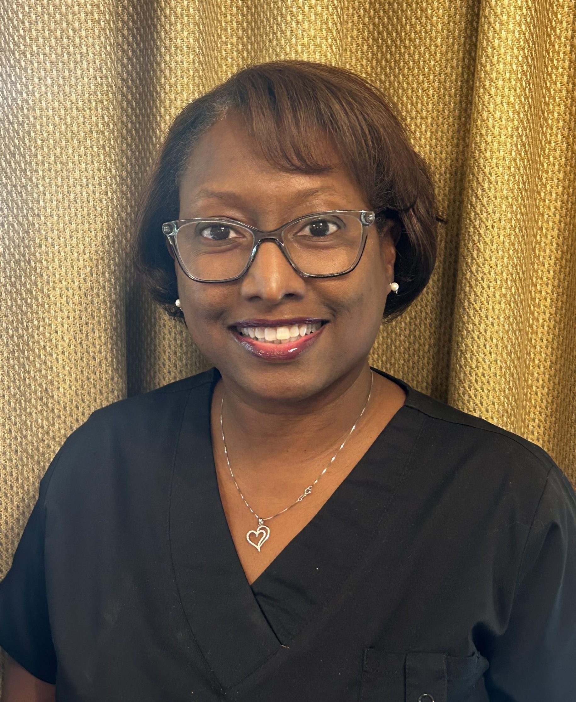 Dr. Tracee Chatman smiling in black scrubs, wearing glasses, professional headshot